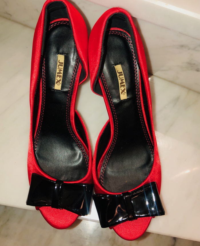 Rote Satin-Pumps mit schwarzer Lackmasche, getragen